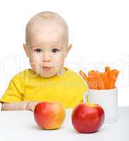 Cute little boy eats carrot and apples