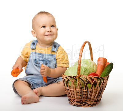 Cute little boy with basket full of vegetables