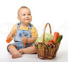 Cute little boy with basket full of vegetables