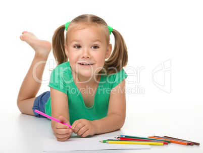 Little girl is drawing while laying on the floor