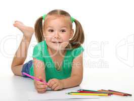 Little girl is drawing while laying on the floor