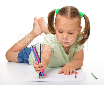 Little girl is drawing while laying on the floor