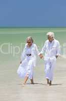 Happy Senior Couple Walking Holding Hands on a Tropical Beach