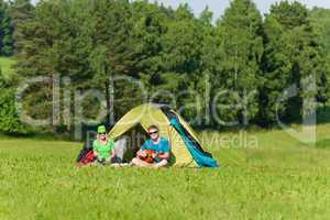 Young camping couple cooking meal play guitar