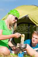 Young camping couple cooking meal outside tent