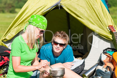 Young camping couple cooking meal outside tent