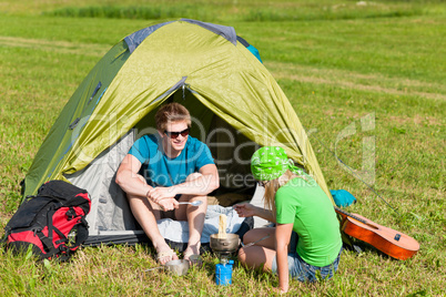 Young camping couple cooking meal outside tent