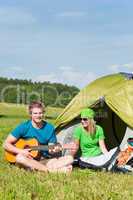 Camping couple playing guitar by tent countryside
