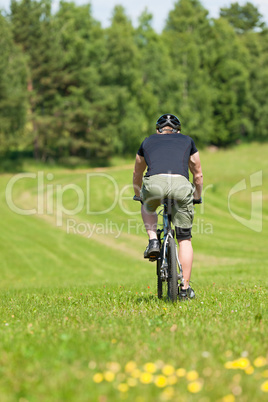 Sportive man mountain biking downhill sunny meadows