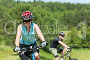 Sport mountain couple biking uphill sunny meadows