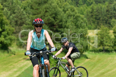 Sport mountain couple biking uphill sunny meadows