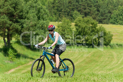 Sport mountain girl biking uphill sunny meadows