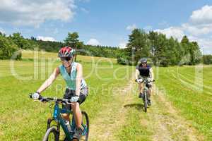 Sport couple riding mountain bicycles in coutryside