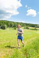 Sportive young man jogging meadows sunny summer