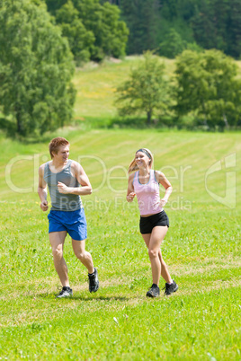 Sportive young couple jogging meadows sunny summer