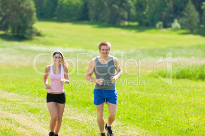 Sportive young couple jogging meadows sunny summer