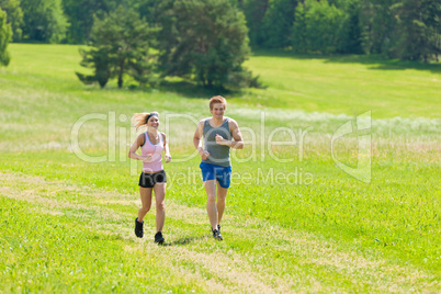 Sportive young couple jogging meadows sunny summer