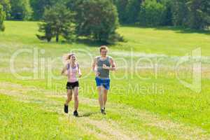 Sportive young couple jogging meadows sunny summer