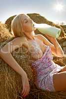 woman with bare breasts sitting on hay and drinking milk
