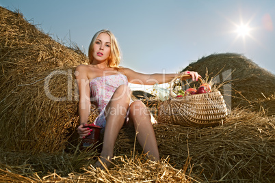 woman sitting on the hay with a basket of fruit and a pitcher of