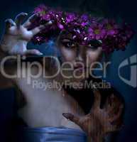 beauty woman portrait with wreath from flowers on head over blue background