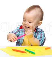 Happy little boy is playing with colorful markers