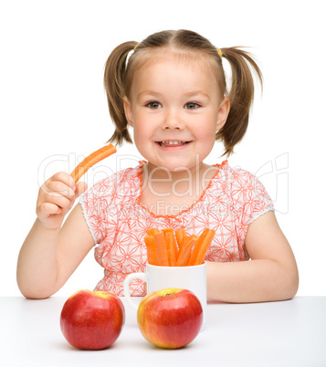 Cute little girl eats carrot and apples