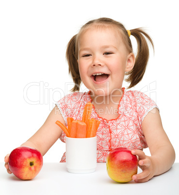 Cute little girl eats carrot and apples