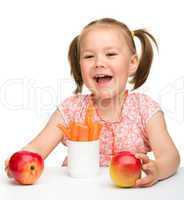 Cute little girl eats carrot and apples