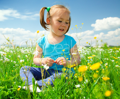 Little girl is playing on green meadow