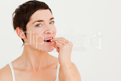 Close up of a young woman taking a pill