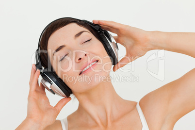 Close up of a delighted brunette listening to music