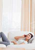 Portrait of a brunette calling while lying on a sofa