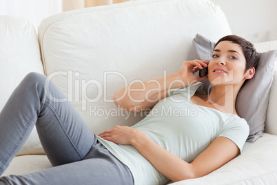 Close up of a  cute brunette calling while lying on a sofa