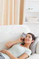 Portrait of a cute brunette calling while lying on a sofa