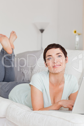 Portrait of a smiling young woman using a laptop in her living room