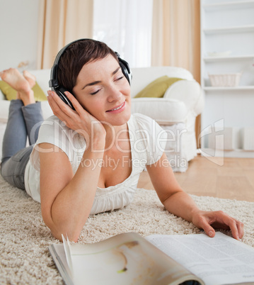 Portrait of a delighted woman with a magazine enjoying some musi