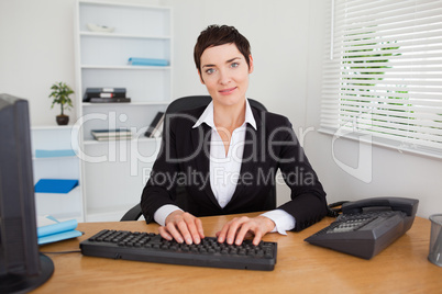 Smiling secretary typing on her keybord