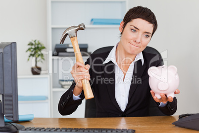Office worker breaking a piggybank with a hammer