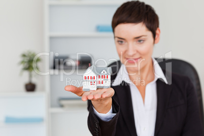 Young brunette showing a house miniature