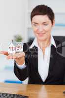 Portrait of a businesswoman showing a miniature house