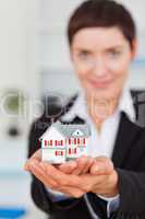 Portrait of a businesswoman holding a miniature house