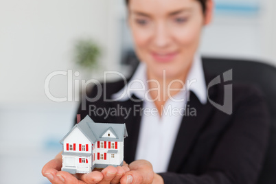 Smiling businesswoman holding a miniature house