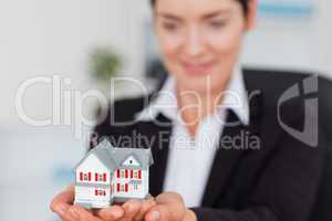 Smiling businesswoman holding a miniature house