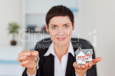 Woman showing a miniature house and a key