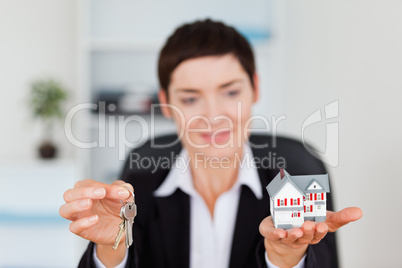 Smiling woman showing a miniature house and a key