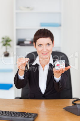 Portrait of a businesswoman showing a miniature house and a key Portrait of a businesswoman showing a miniature house and a key