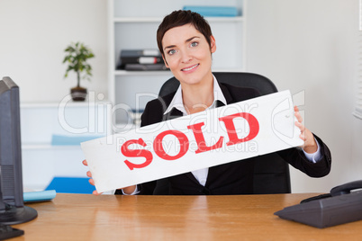 Happy real estate agent with a sold panel