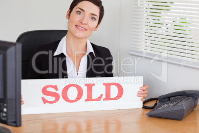 Smiling real estate agent with a sold panel