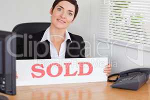 Smiling real estate agent with a sold panel